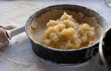 Making an apple pie. Baking pan with short crust pastry dough and cooked apples
