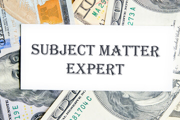 Text Subject Matter Expert written on a white card against the background of banknotes