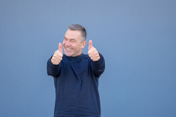 Enthusiastic middle aged man giving a double thumbs up gesture with a beaming smile