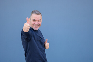 Enthusiastic middle aged man giving a thumbs up gesture with a beaming smile
