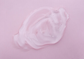 Cosmetic gel for face and body. Liquid cosmetic gel or serum lotion texture smudge on a pink background.Gel texture with bubbles 