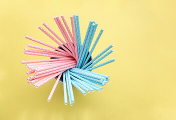 Pink polka dot paper straws and light blue polka dot paper straws on yellow background. Drinking...