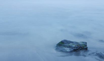 Rock in blurred out sea due to long-exposure phothgraph