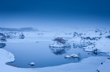 A body of water with snow covered land and rocks