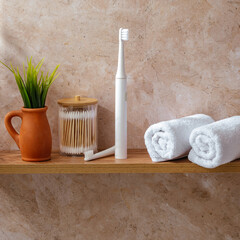 Fototapeta na wymiar an electric toothbrush and white towels on a shelf in the bathroom