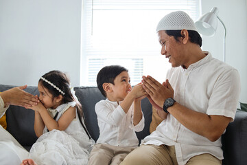 Muslim family and kid greeting and asking forgiveness shaking hand during Eid Mubarak