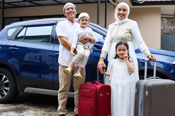 Asian muslim family holding suitcases ready to travel by car or mudik during Eid Mubarak moment