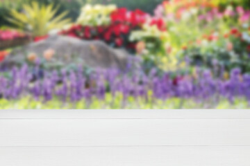 Wooden white empty table in outdoor blurred colourful flowers background. empty rustic wooden table. Mock up for display of product.