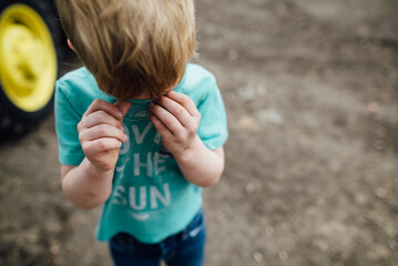 Overhead view of young boy using a shirt to wipe his face