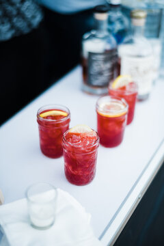 Red drinks in mason jars with lemon garnish