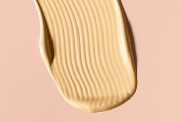 creamy cosmetic texture of golden shining color cosmetic smear on beige background close-up
