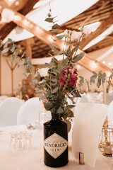 Coziness and style. Modern event design. Table setting at wedding reception. Floral compositions with beautiful flowers and greenery, candles, laying and plates on decorated table