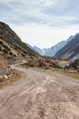 Country gravel road leading to mountains. Kyrgyz republic, Kyrgyzstan nature. Mountain natural landscape in brown colors. Travel destination