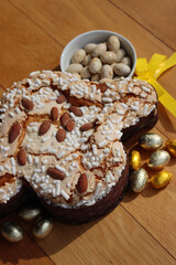 Colomba Pasquale. Sweet Easter cake with chocolate eggs wrapped in foil. Italian traditional pastry on wooden table