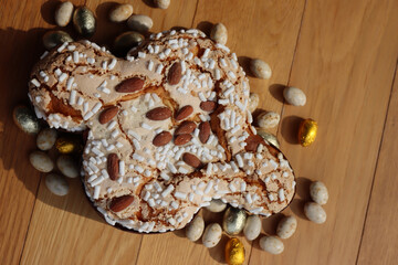 Colomba Pasquale. Sweet Easter cake with chocolate eggs wrapped in foil. Italian traditional pastry on wooden table