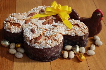 Colomba Pasquale. Sweet Easter cake with dark chocolate hen and eggs wrapped in foil. Italian traditional pastry on wooden table