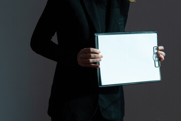 A white sheet of paper on a writing tablet is brightly illuminated by sunlight in the hands of a woman