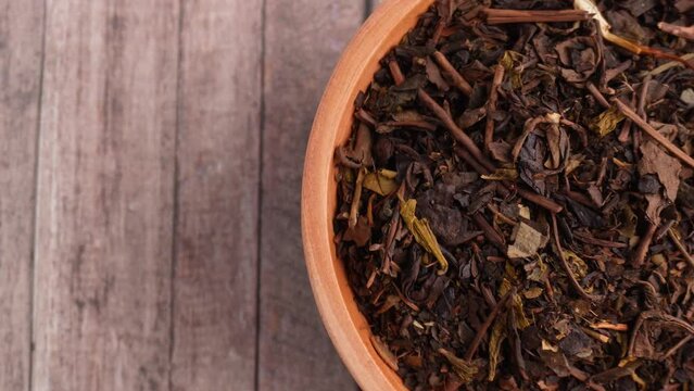 wooden bowl filled dried tea leaves half midsection overhead shot