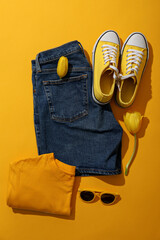 Female spring outfit and flowers on yellow background, top view