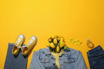 Female spring outfit and flowers on yellow background, space for text