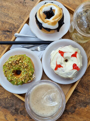 bunch of flavours donut and drinks in white plates on wooden table