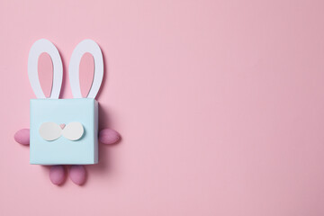 Blue gift box with rabbit ears on pink background