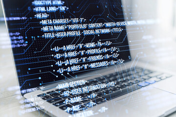 A modern laptop displaying HTML coding language on the screen with graphical user interface...
