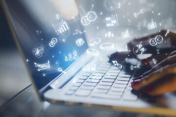 A close-up image of a person typing on a laptop with glowing business-related graphics hovering...