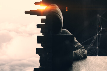Hacker with laptop using laptop at desk on abstract concrete city and sunset polygonal background....