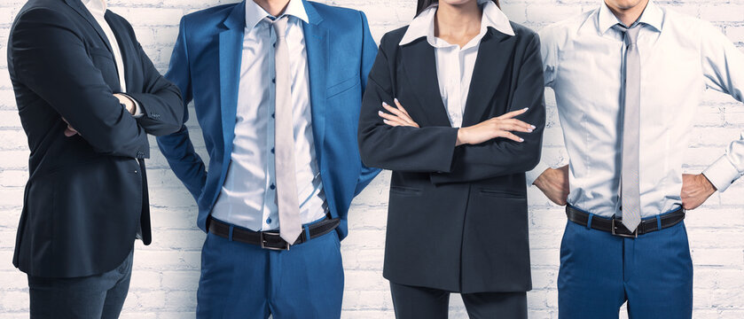 Four professional individuals in business attire exude confidence and teamwork against a textured white wall