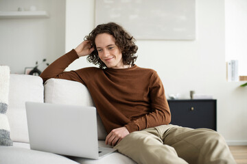 Handsome young man using laptop computer at home. Student men resting in his room. Home work or study, freelance, online learning and casual business concept - 746322234