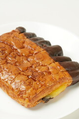 Indulge in our delectable chocolate banana pastry, featuring a rich blend of sweet banana cream and chocolate, encased in a crisp chocolate-covered shell. Photographed against a white backdrop.