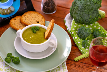 Bowl with handmade broccoli soup and croutons, fresh raw green broccoli on wooden table. Healthy nutrition, eat vegetables, eating,  vegetarian, vegan cuisine.