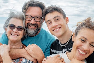 Cheerful group of mothers and sons, multi-generation family, have fun outdoors by the sea. Four...