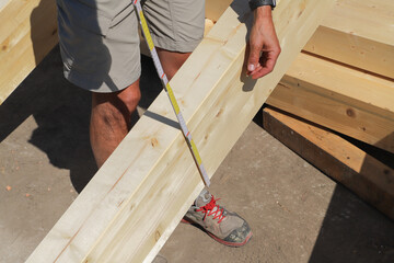 a carpenter measures a wooden beam
