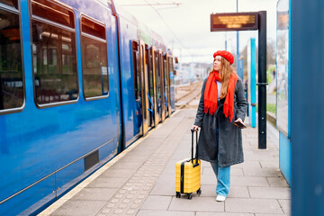 Happy tourist woman with small yellow luggage at the train station exited about oncoming journey....