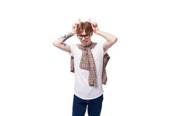 portrait of a stylish red-haired guy in glasses and a plaid shirt on a studio background