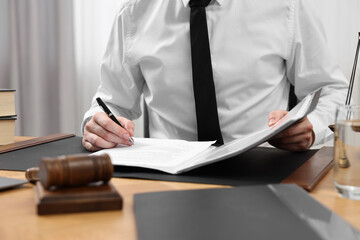 Lawyer working with documents at table indoors, closeup