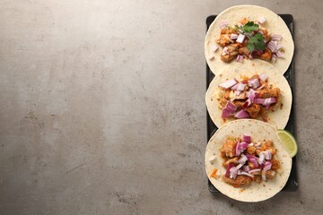 Delicious tacos with vegetables, meat and lime on grey textured table, top view. Space for text