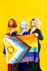 Drag queens standing together with Pride flag