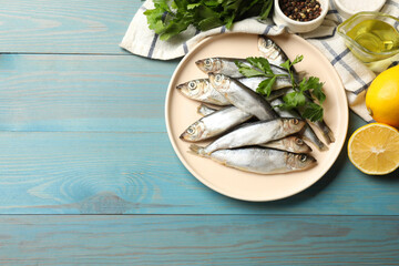 Fresh raw sprats, parsley and other products on light blue wooden table, flat lay. Space for text