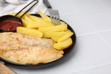 Delicious fish and chips served on white tiled table, closeup
