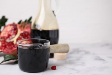 Tasty pomegranate sauce on white marble table, closeup. Space for text