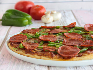 Pepperoni Pizza topping with capsicum, mushroom, tomato and olives served in dish isolated on table side view of arabic fastfood