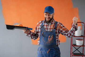 Painter man with beard standing near painting wall celebrating a victory