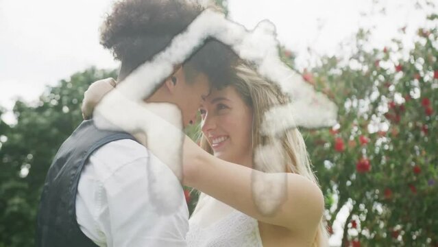 Animation of cloud house over happy diverse couple embracing in garden on wedding day