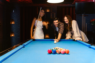 Young diversity group of people playing pool together with smile, enjoyment and fun. Young people...