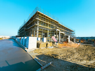 Scaffolding at the construction site of a multi-storey building. construction site with scaffolding and building materials, blue sky background