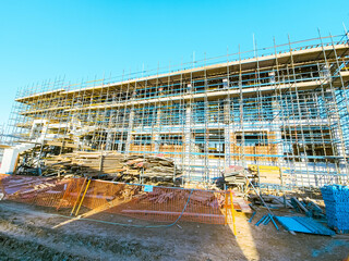 Scaffolding at the construction site of a multi-storey building. construction site with scaffolding and building materials, blue sky background