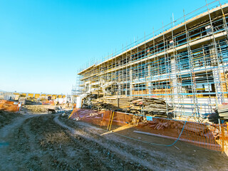Scaffolding at the construction site of a multi-storey building. construction site with scaffolding and building materials, blue sky background